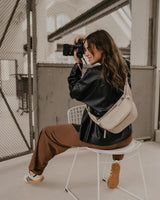 Donna che scatta una foto con una macchina fotografica, seduta su una sedia all'aperto.