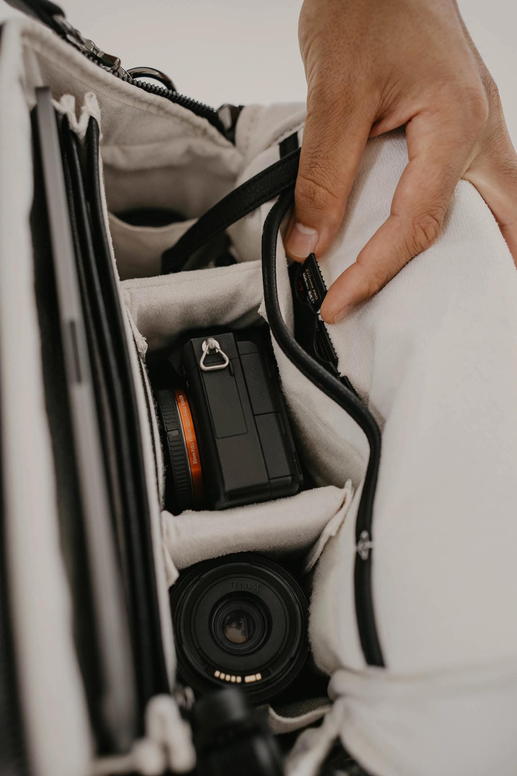 Camera equipment inside a bag with a hand adjusting the strap.