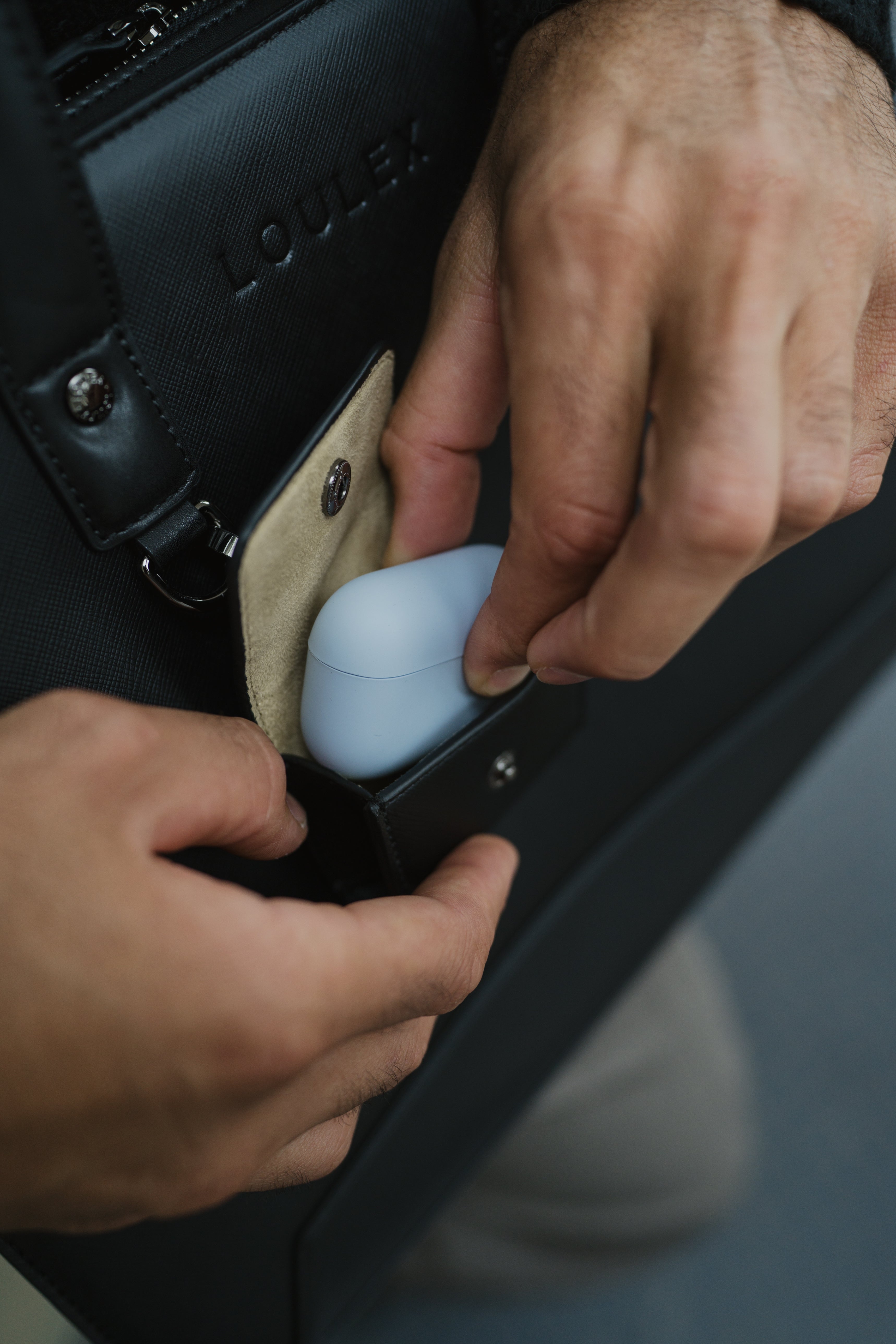 Person placing a blue object into a black bag with 'LOULEX' branding.