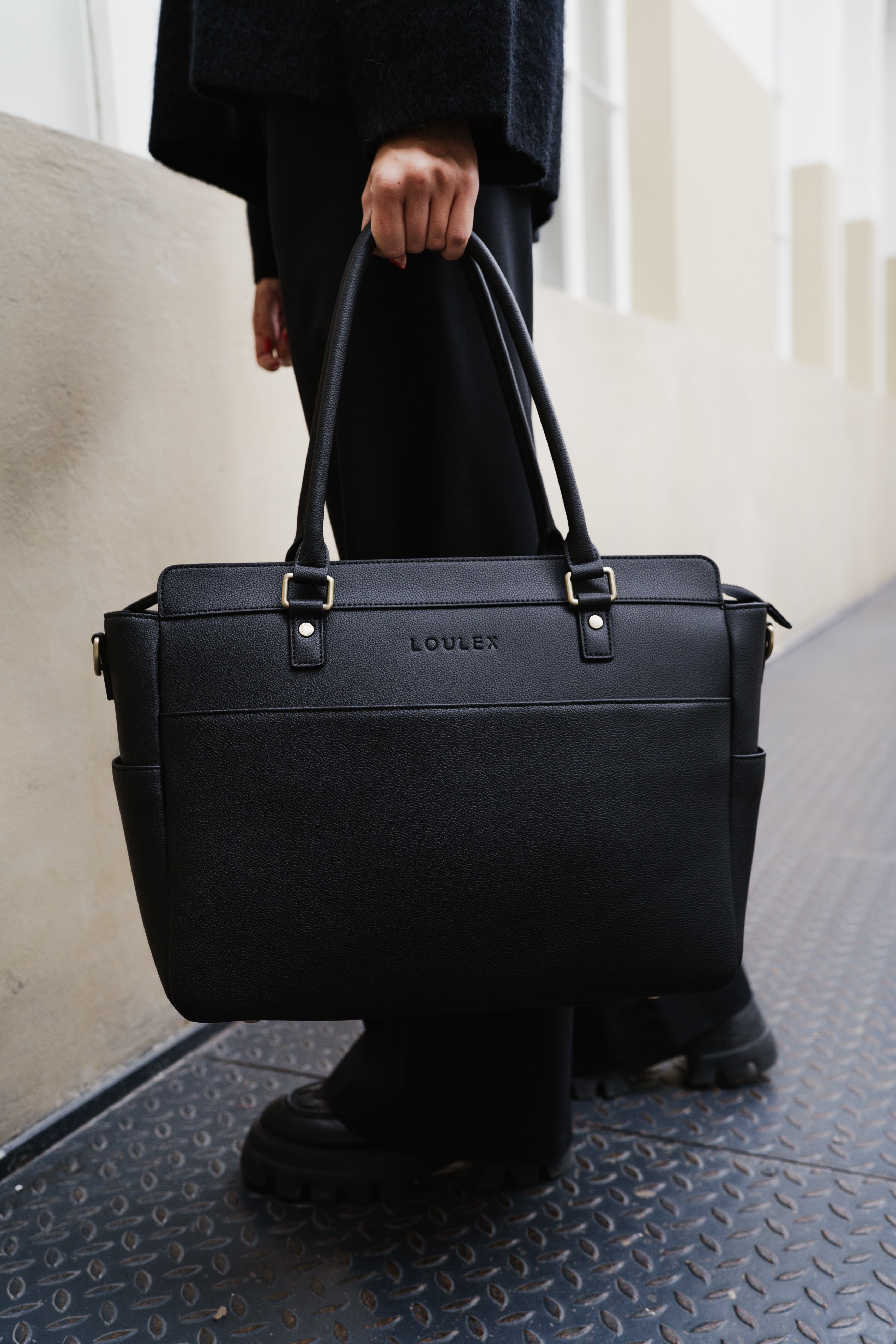 Person holding a black leather briefcase with 'LOVLER' branding.