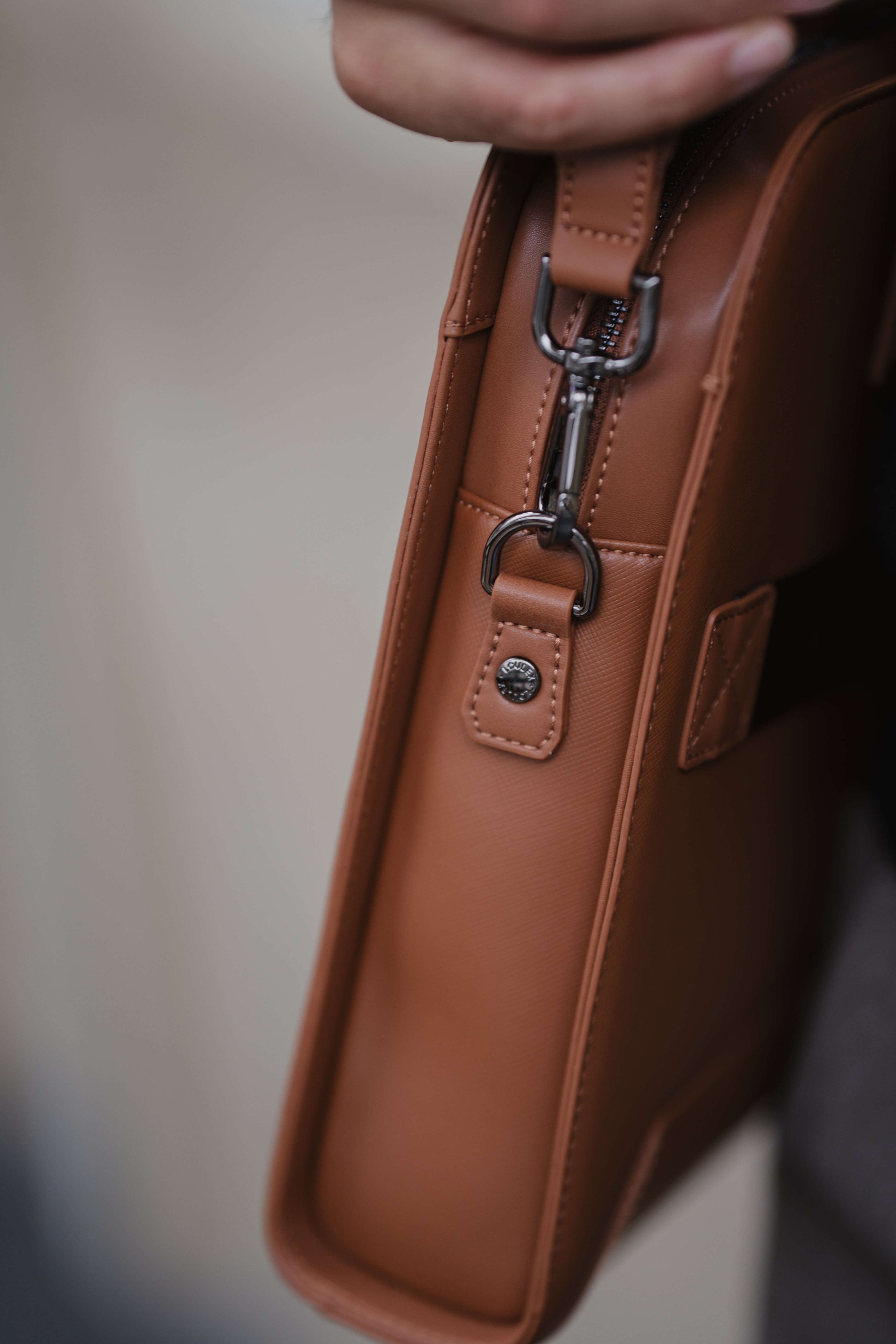 Close-up of a brown leather bag with a metal clasp on a blurred background
