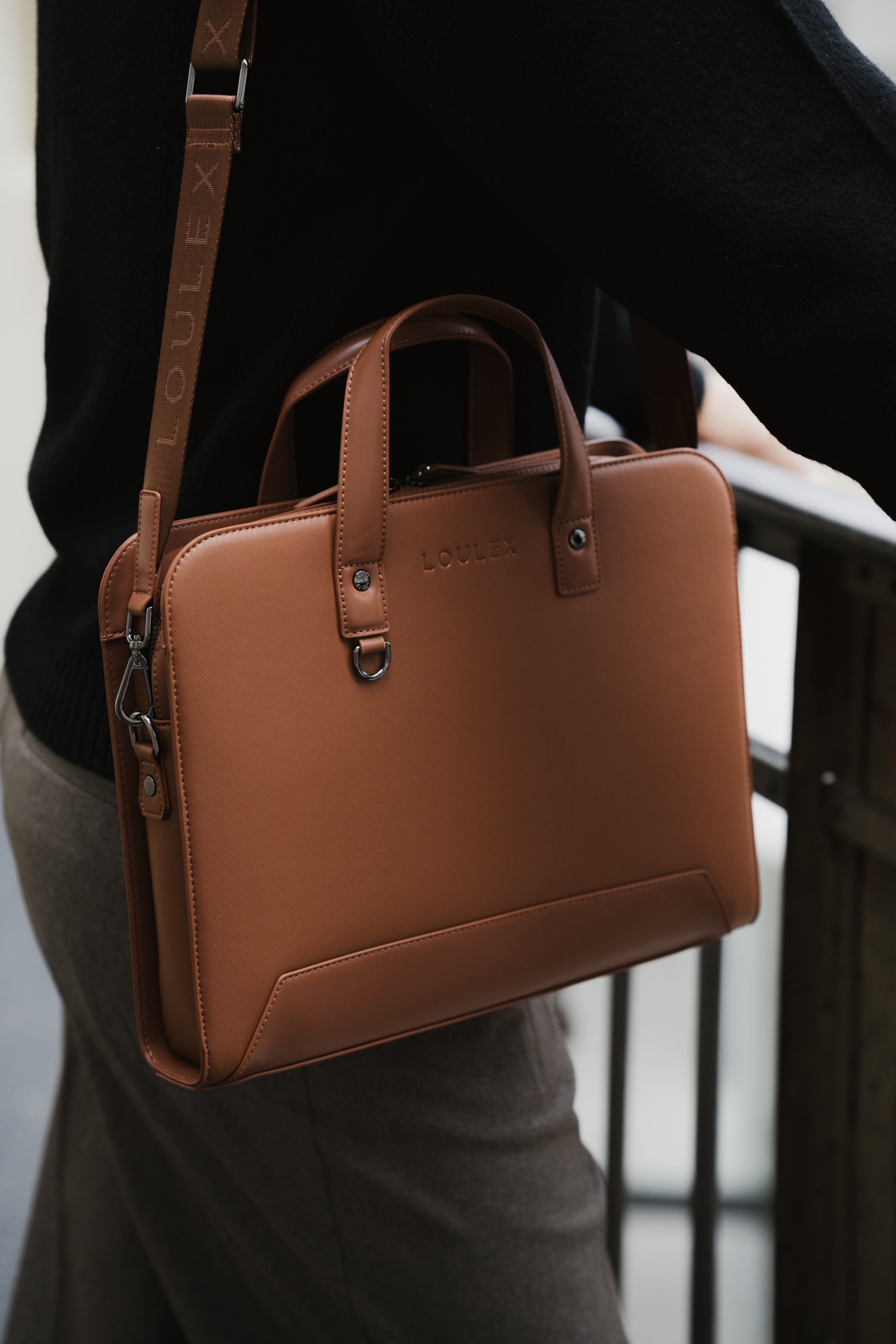 Brown leather briefcase held by a person with a blurred background