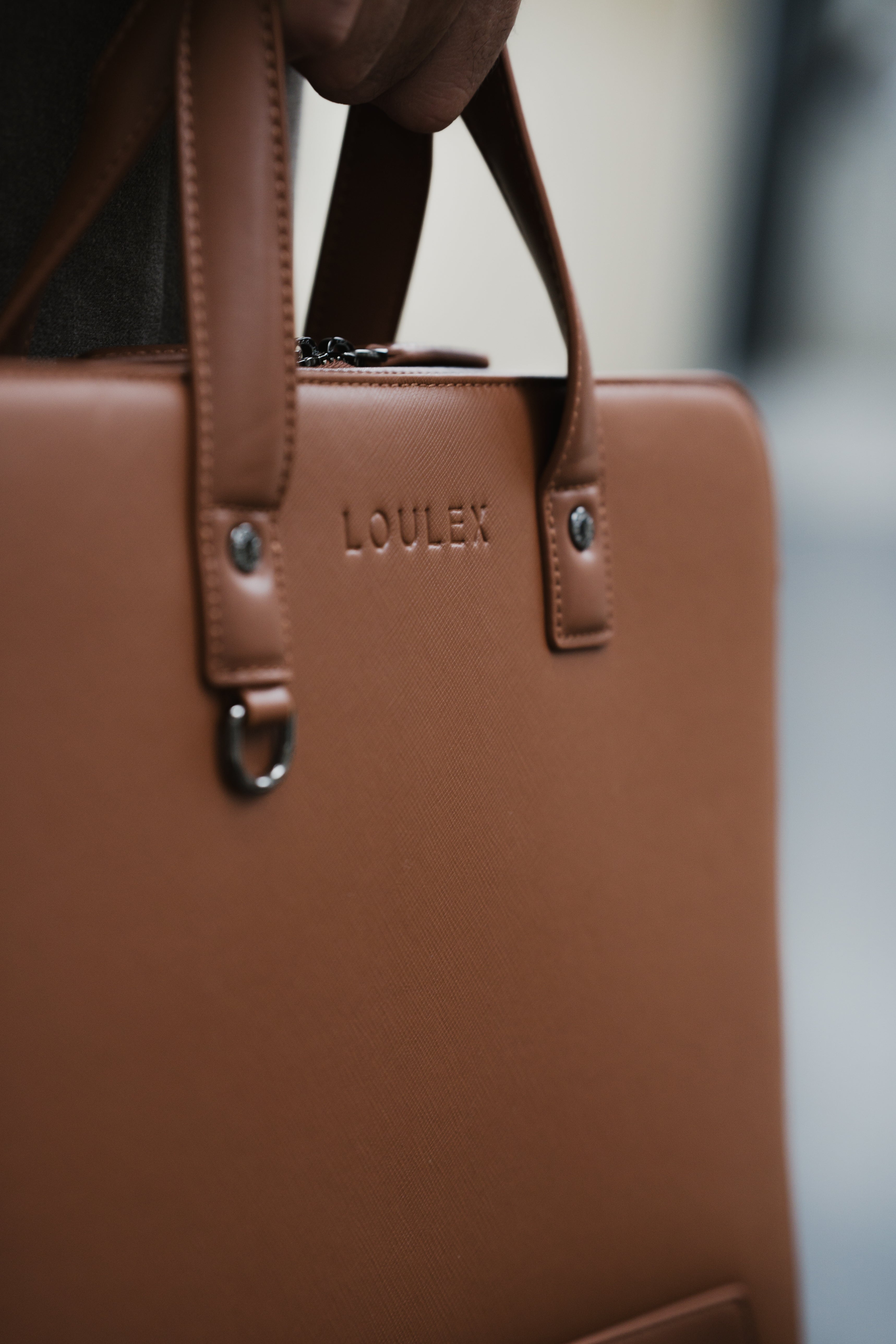 Brown leather bag with 'LOULEX' branding on a blurred background