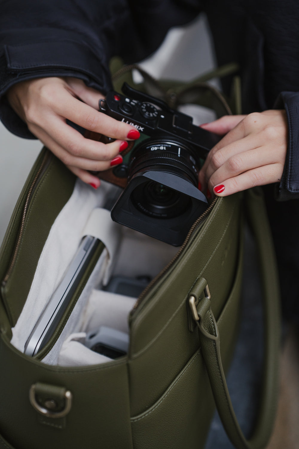 Persoon die een camera uit een open groene tas haalt