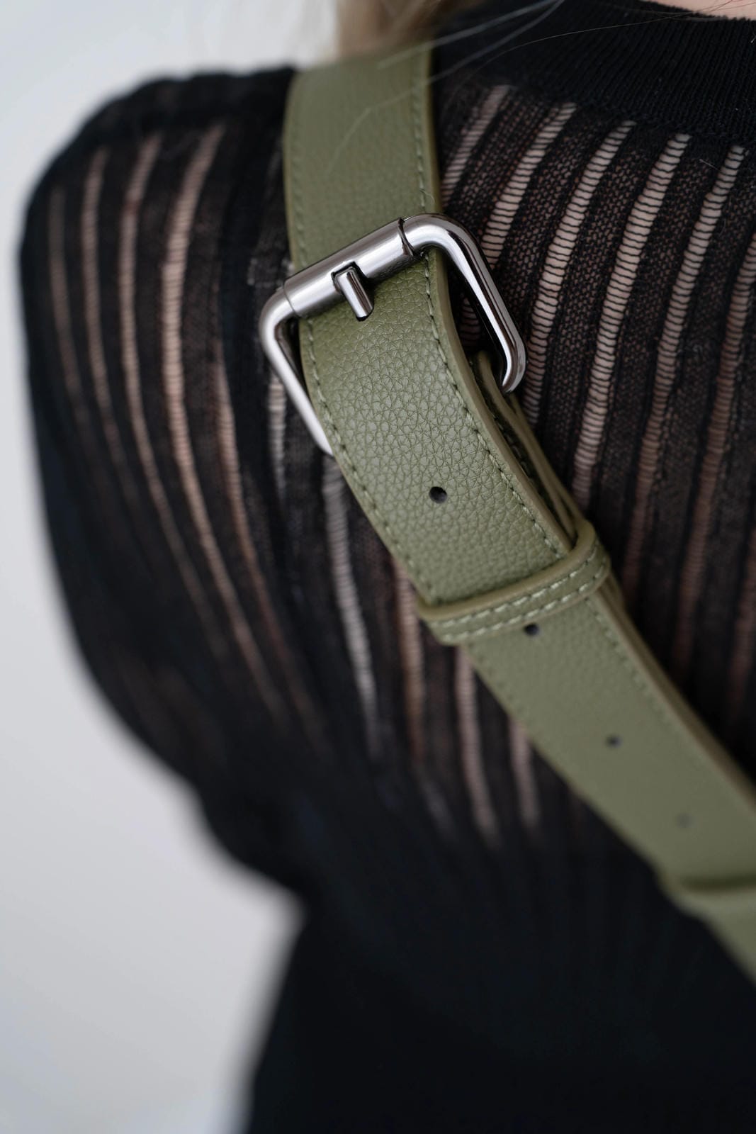 Green leather strap with silver buckle on a textured surface