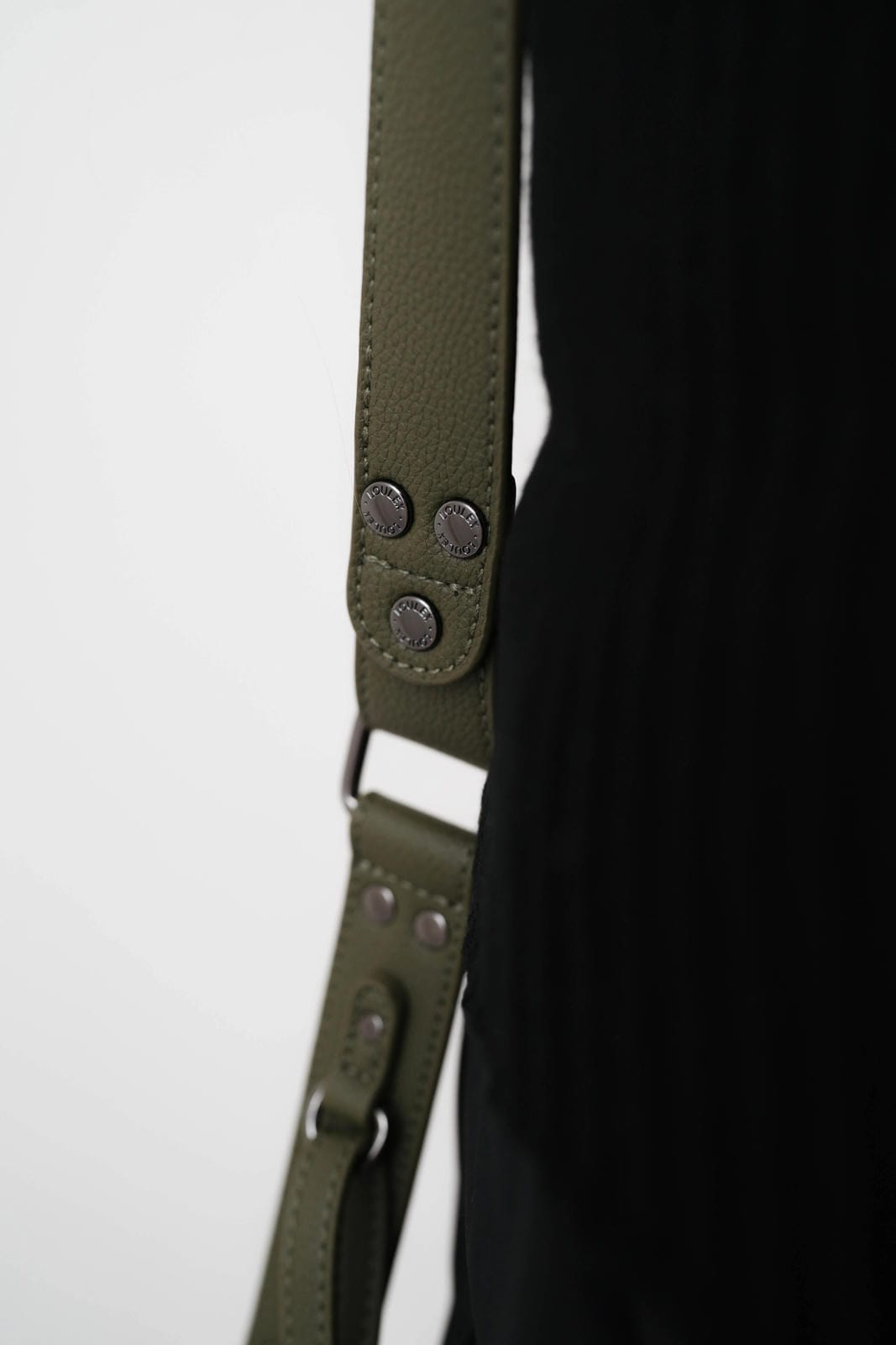 Close-up of a green leather strap with metal hardware on a white background
