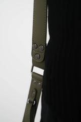 Close-up van een groene leren riem met metalen details op een witte achtergrond