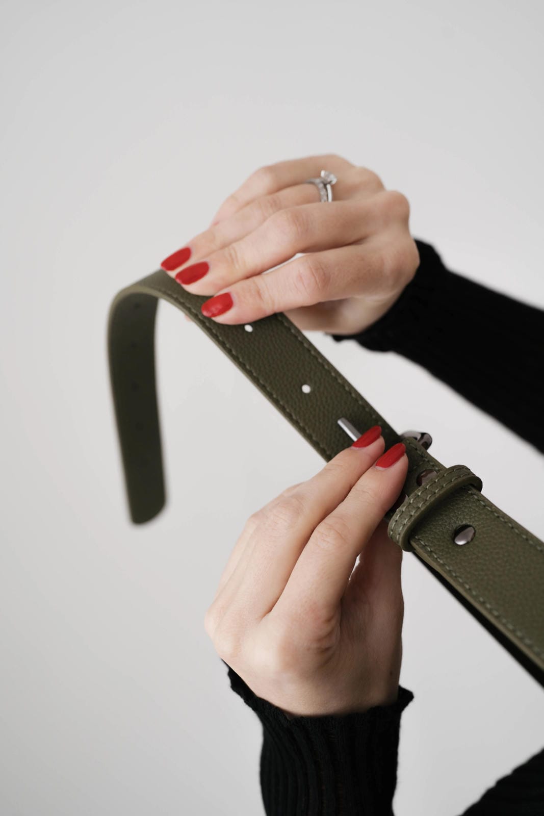 Person adjusting a green belt with a plain background