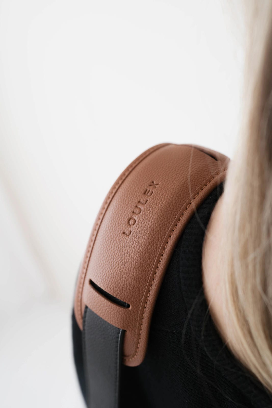 Brown leather headband with 'LOUREX' branding on a blurred background