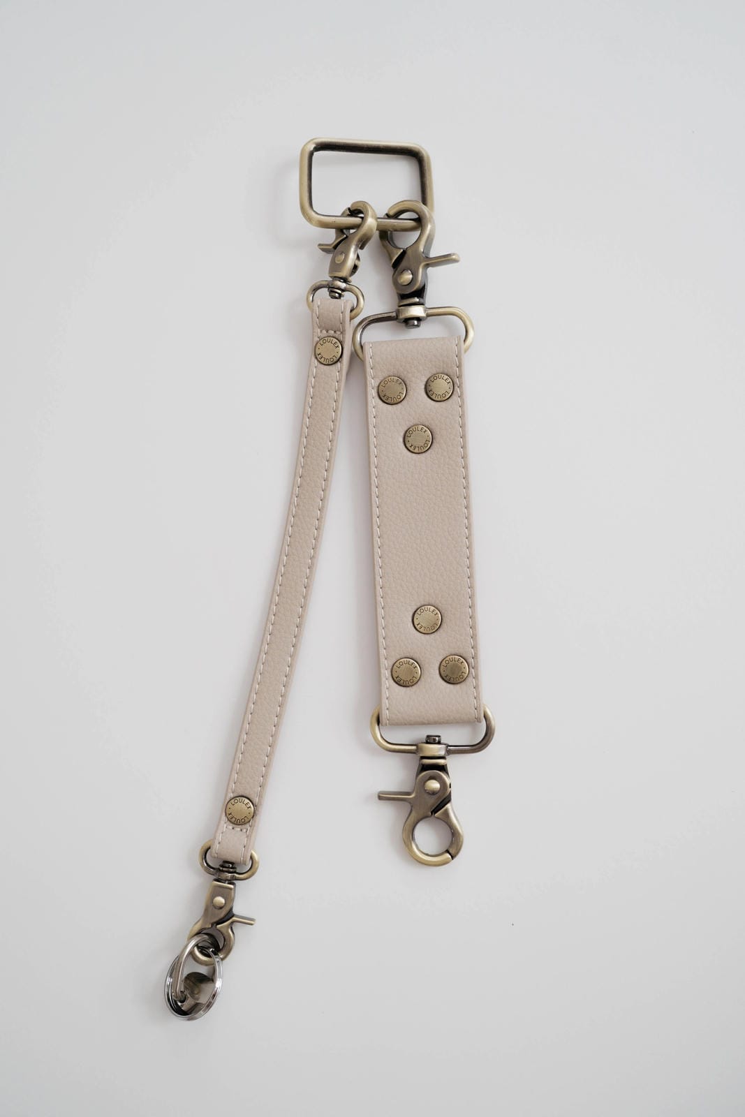 Light beige leather strap with metal hardware on a white background
