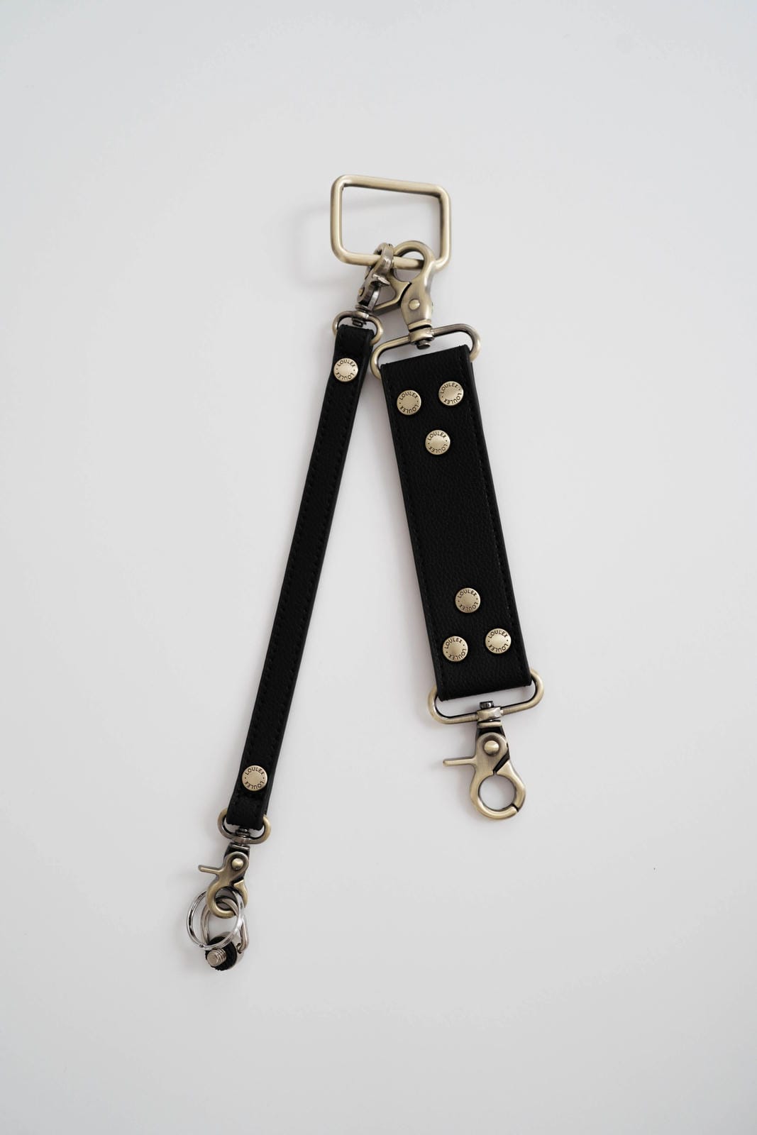 Black leather strap with silver hardware on a white background