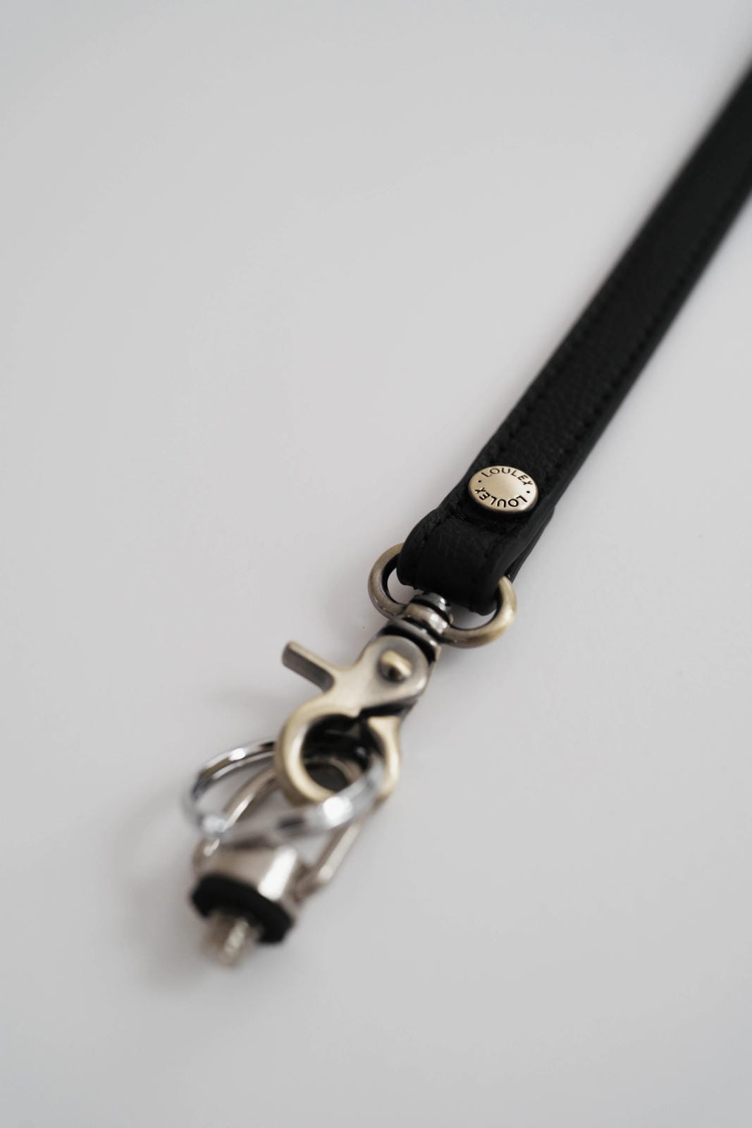 Black leather strap with silver clasp on a light gray background