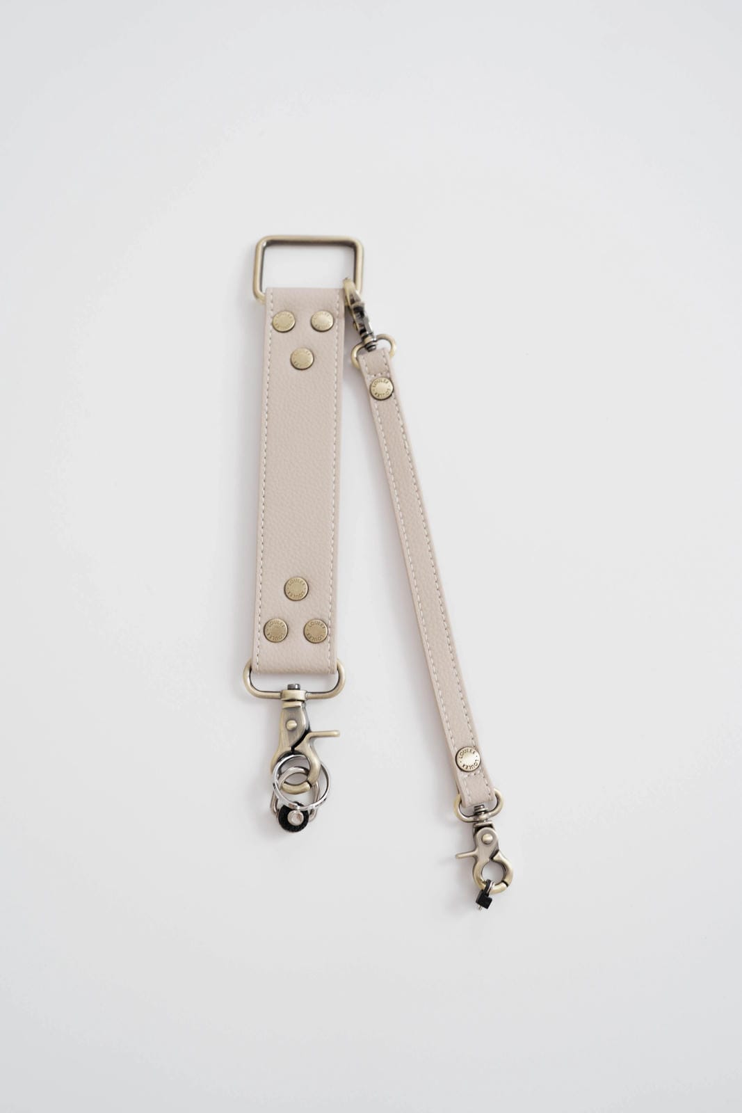 Beige leather strap with metal hardware on a white background