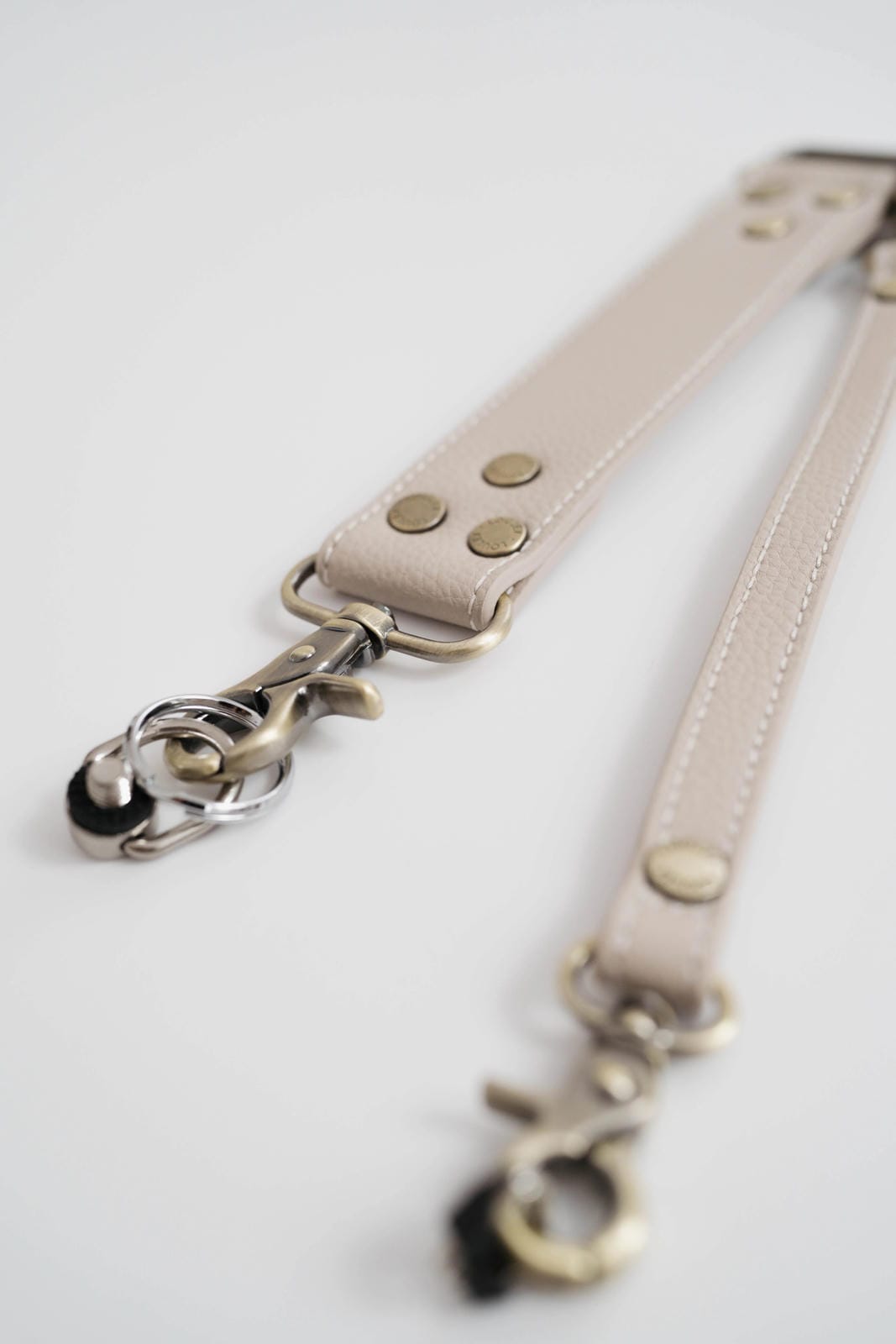 Beige leather strap with metal hardware on a light gray background