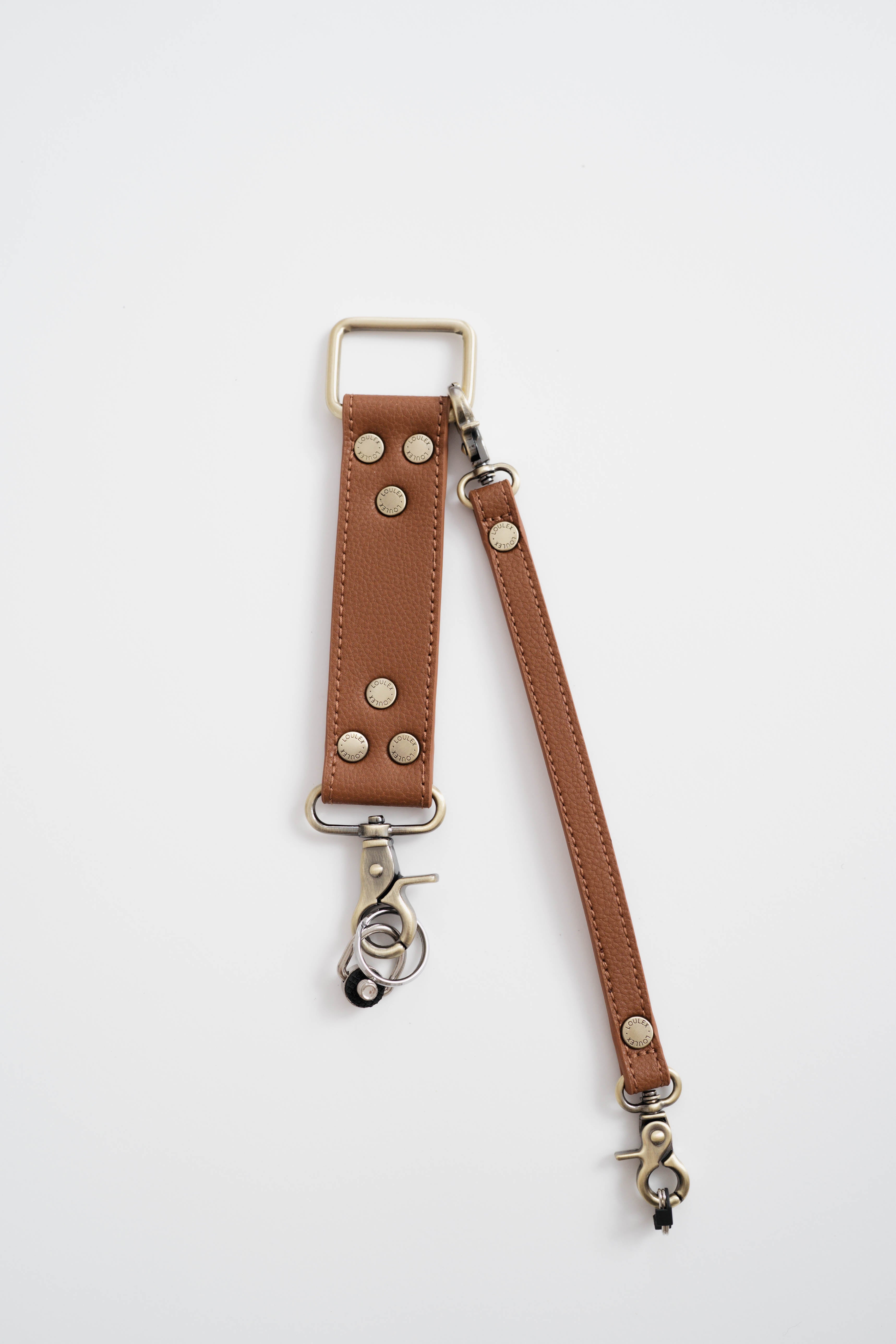 Four camera straps in different colors (black, brown, white, and green) with metal D-rings and clips attached.