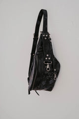 Zaino in pelle nera con dettagli borchiati su sfondo grigio chiaro