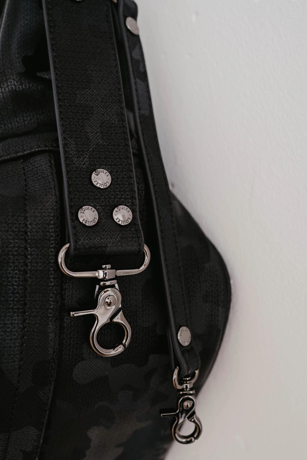 Black bag strap with silver hardware on a white background