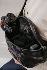 Persona con una macchina fotografica e una borsa con motivi floreali e scomparti.