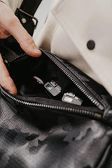 Persona che apre una borsa di pelle nera per mostrare prodotti per la cura personale.