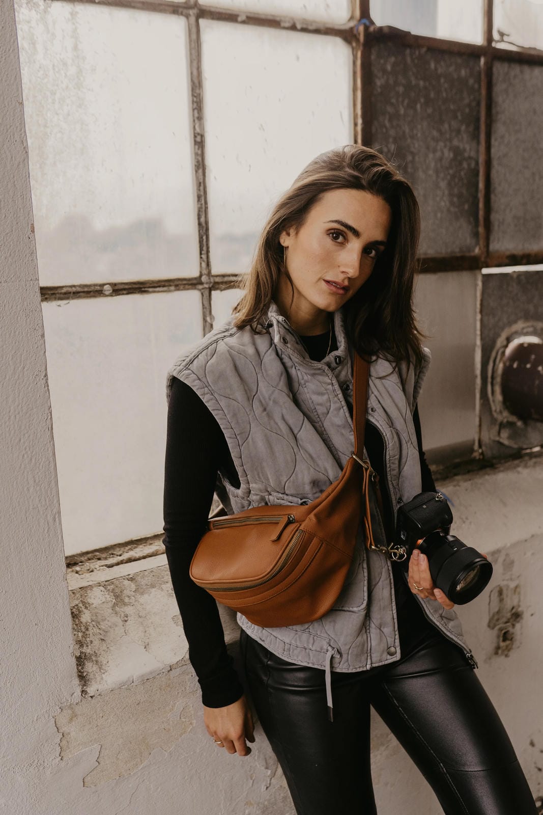 A stylish couple showcasing loulex leather bags, featuring a large cream tote bag and a tan leather messenger camera bag.