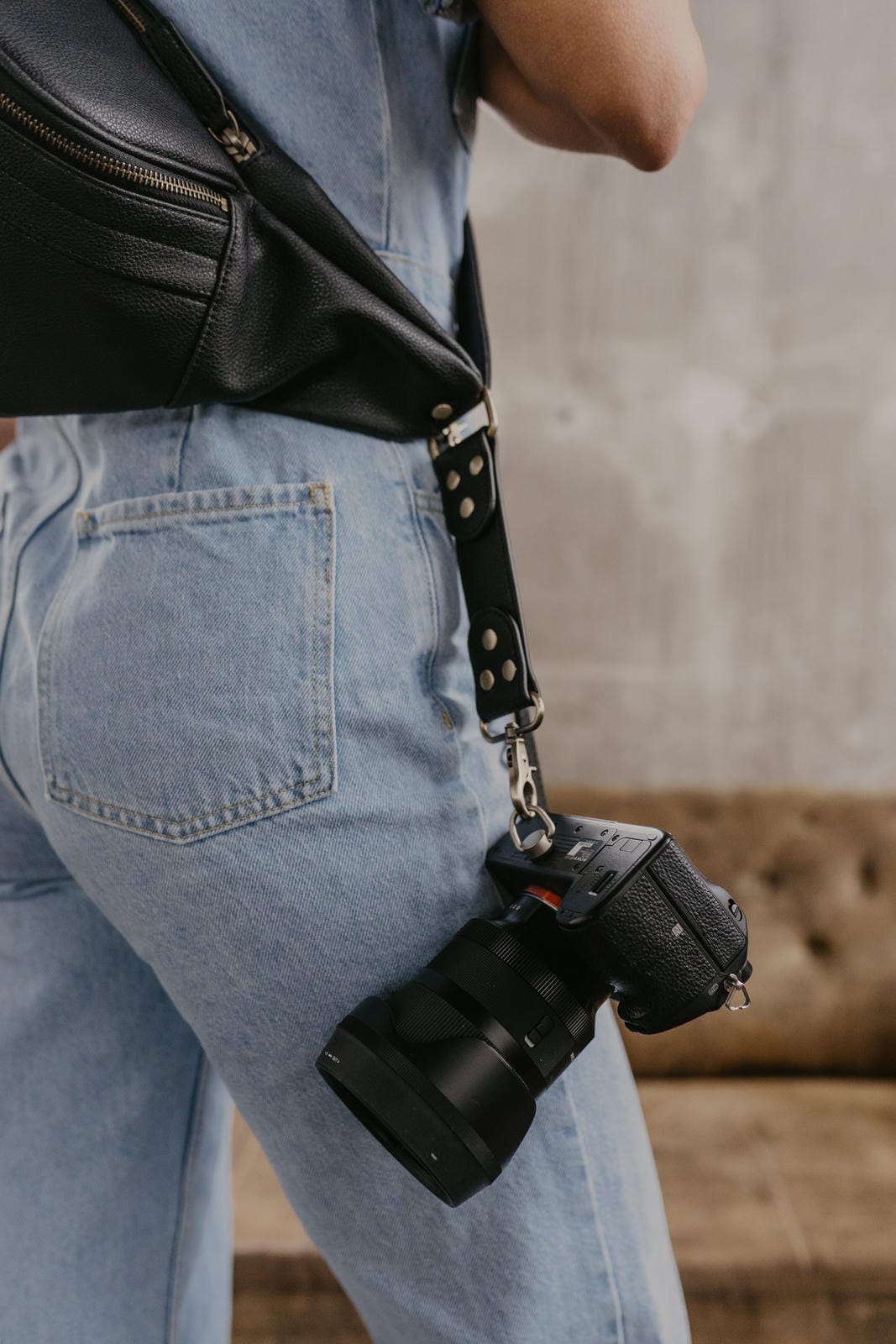 Person wearing a black leather bag over one shoulder with a blurred background