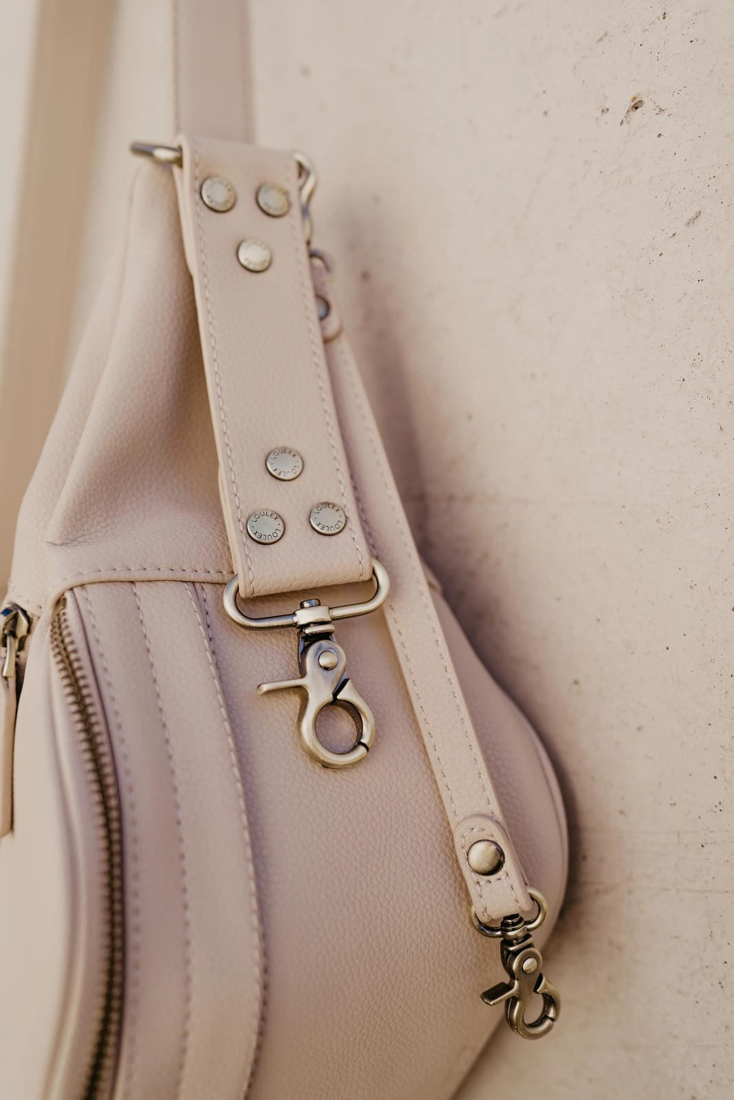 Close-up of a beige handbag with a strap and zipper details.