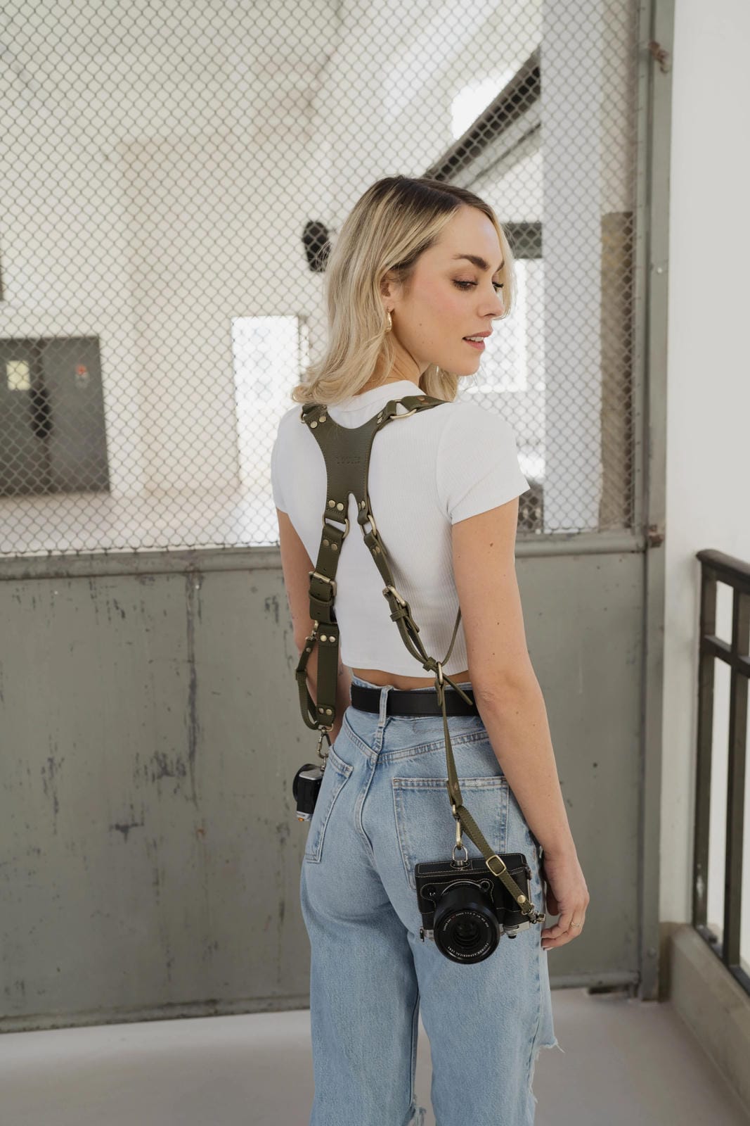 Person wearing suspenders with a camera around their neck in an industrial setting