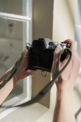 Persona sosteniendo una cámara vintage con un fondo borroso.