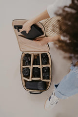 Persona che apre una borsa fotografica con diverse fotocamere all'interno su uno sfondo chiaro