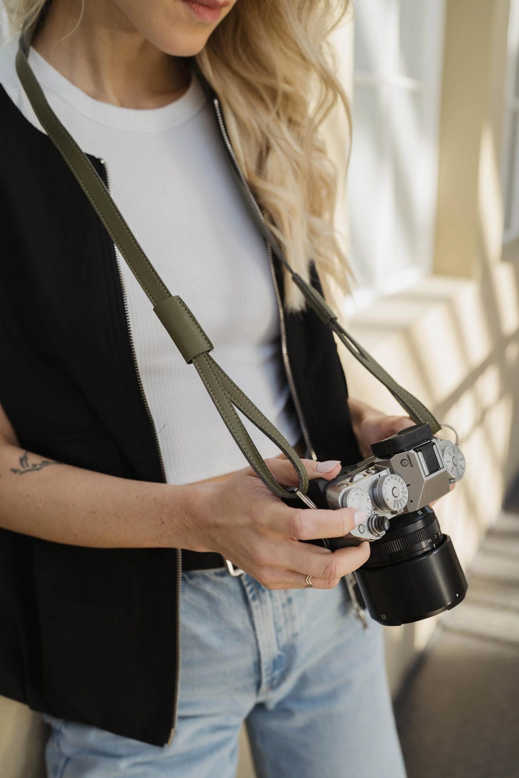 Personne tenant un appareil photo avec une sangle, arrière-plan flou