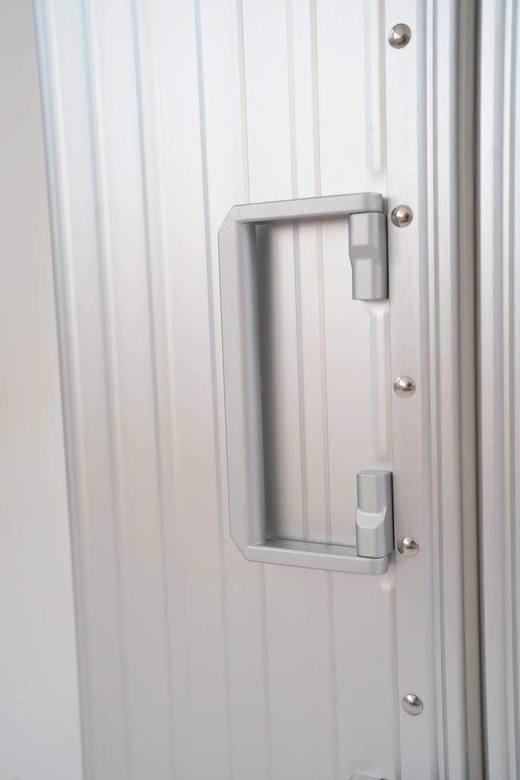 Metallic door handle on a white door with a grid pattern