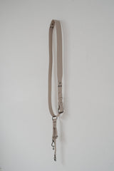 Beige leren band met metalen hardware op een witte achtergrond