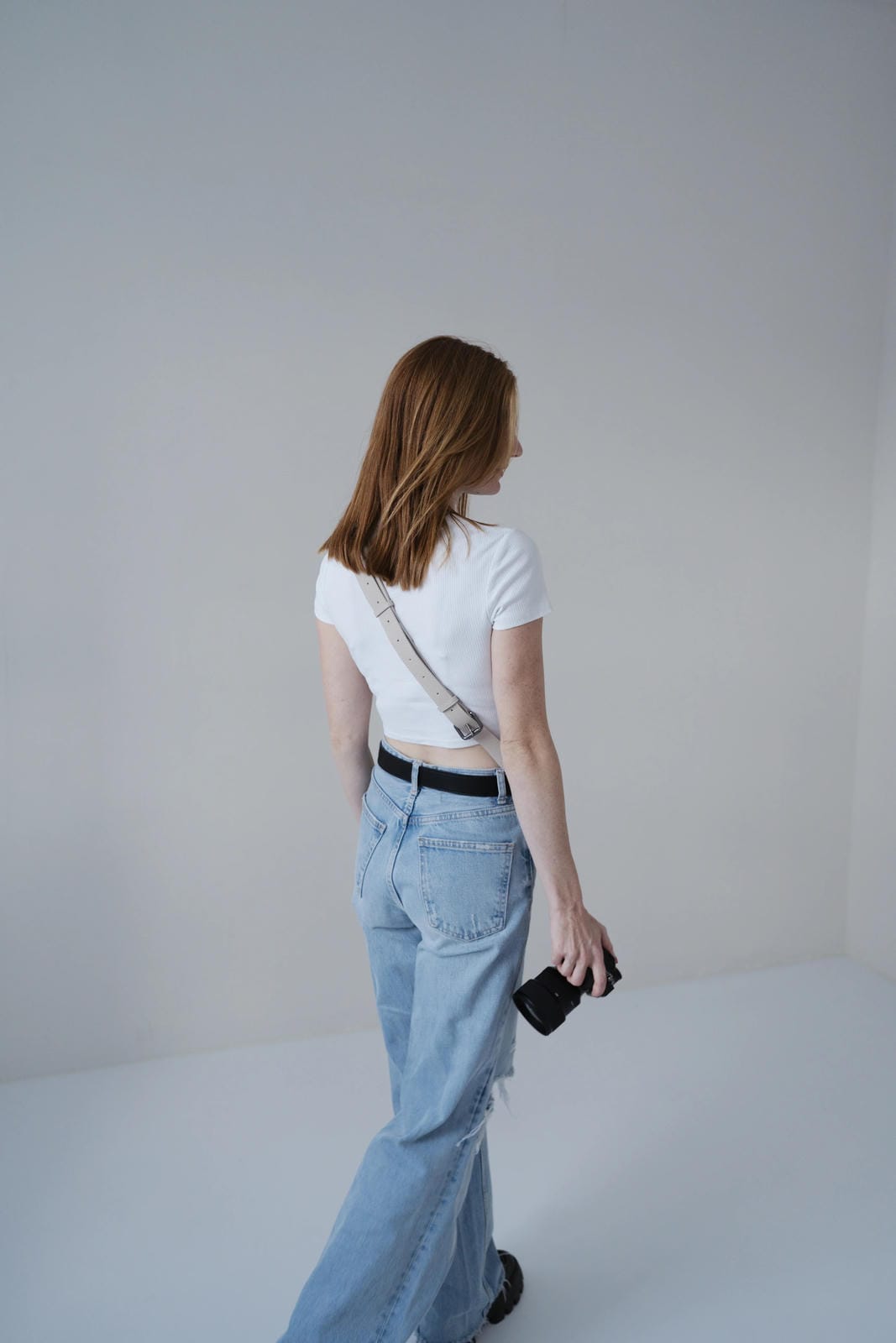 Person wearing a white top and light blue jeans against a plain background