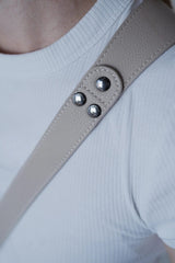 Close-up van een beige riem met metalen knopen op een witte achtergrond