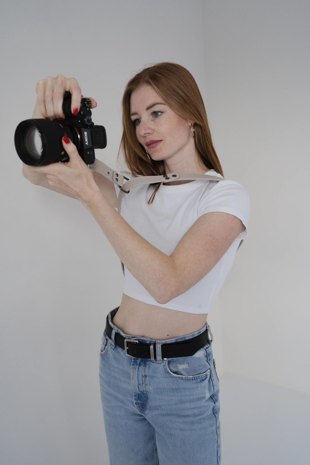 Woman holding a camera against a plain background