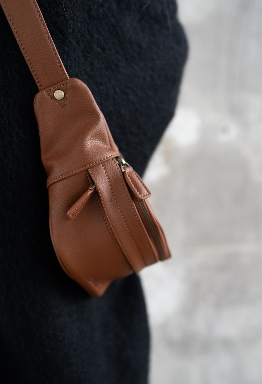 Brown leather bag with a strap on a blurred background