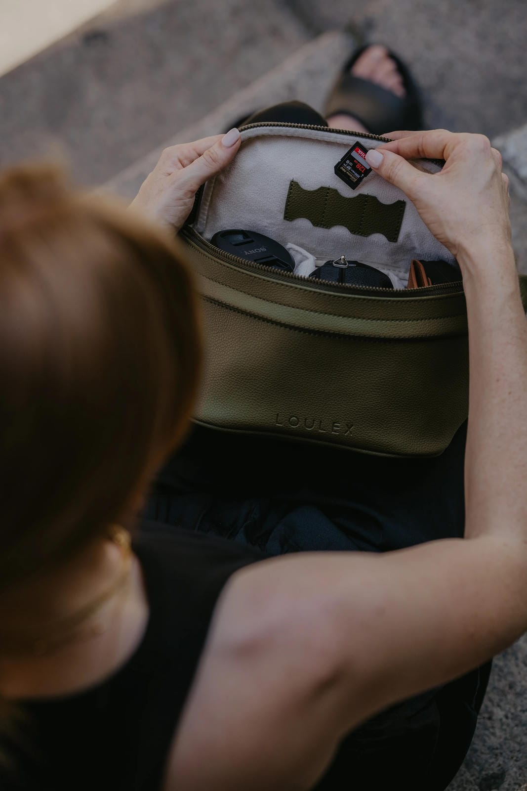 Person opening a beige bag with a brand logo on a textured surface