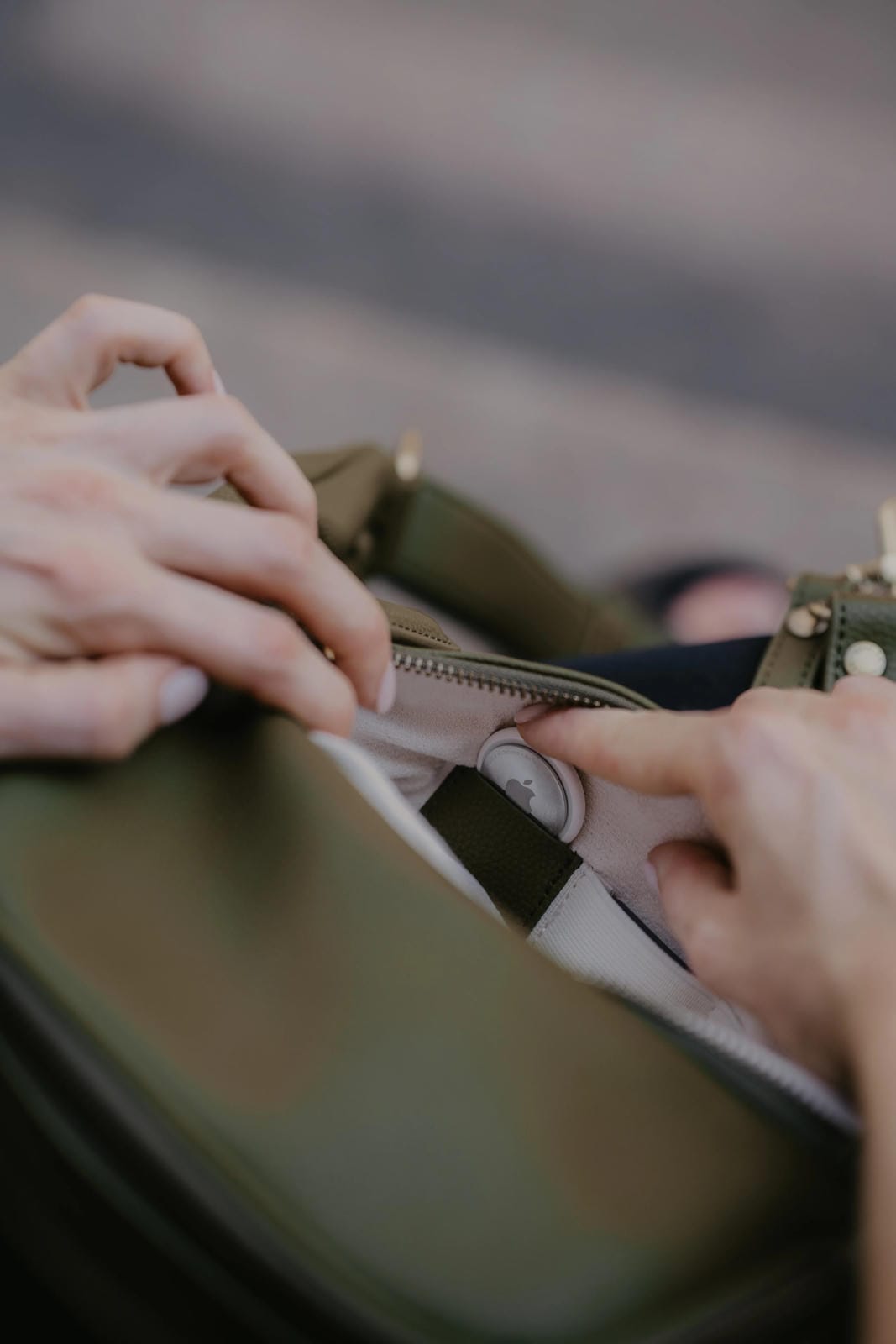 Close-up of hands zipping a green bag with a blurred background