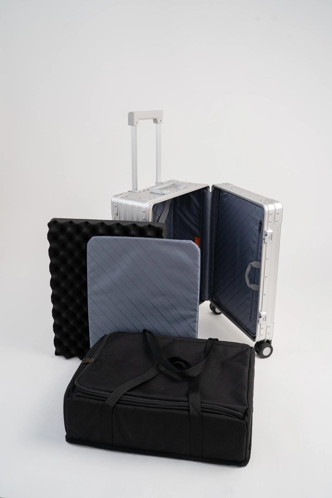 Collection of travel bags including a black suitcase, silver rolling suitcase, and a black duffel bag on a white background.