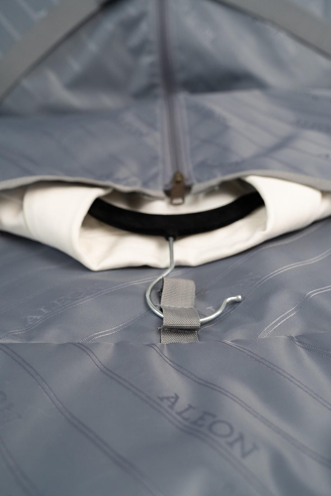 Close-up of a gray umbrella with a visible brand logo on a matching gray background.