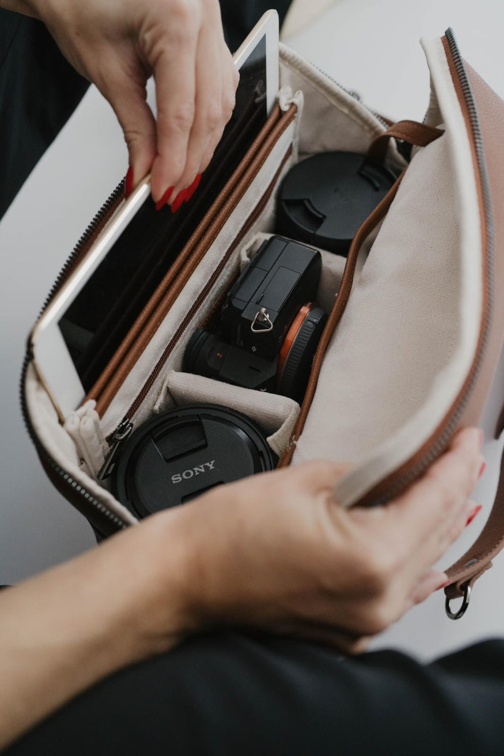 Persona abriendo una bolsa de cámara con una cámara Sony en su interior.