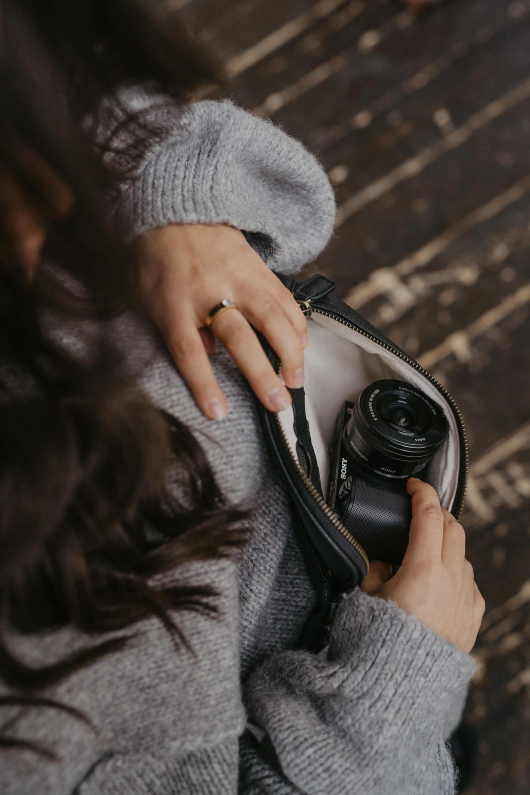 Person holding a camera in a pouch on a wooden floor