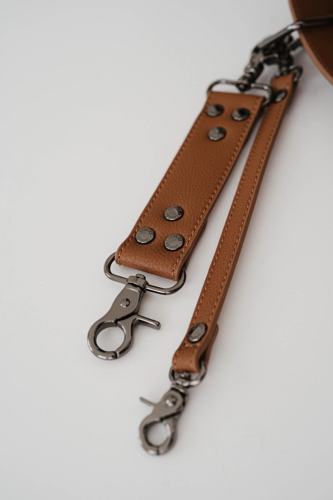 Brown leather strap with metal hooks on a white background