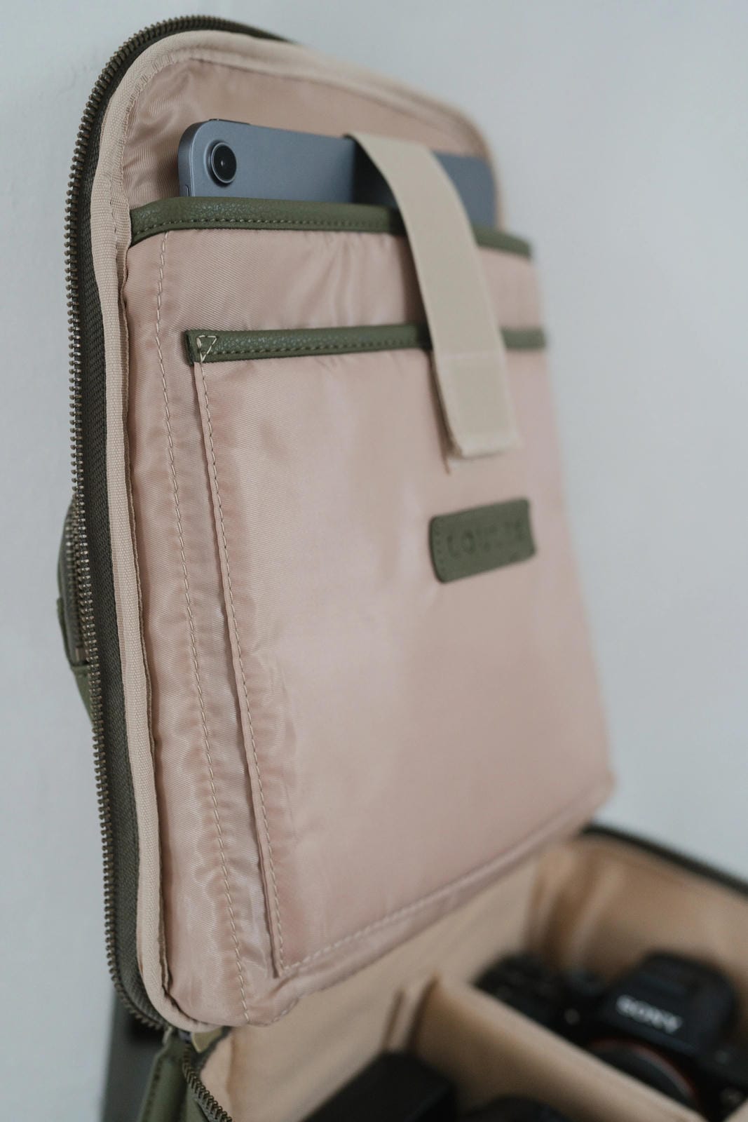 Beige and green bag with a phone inside on a white background