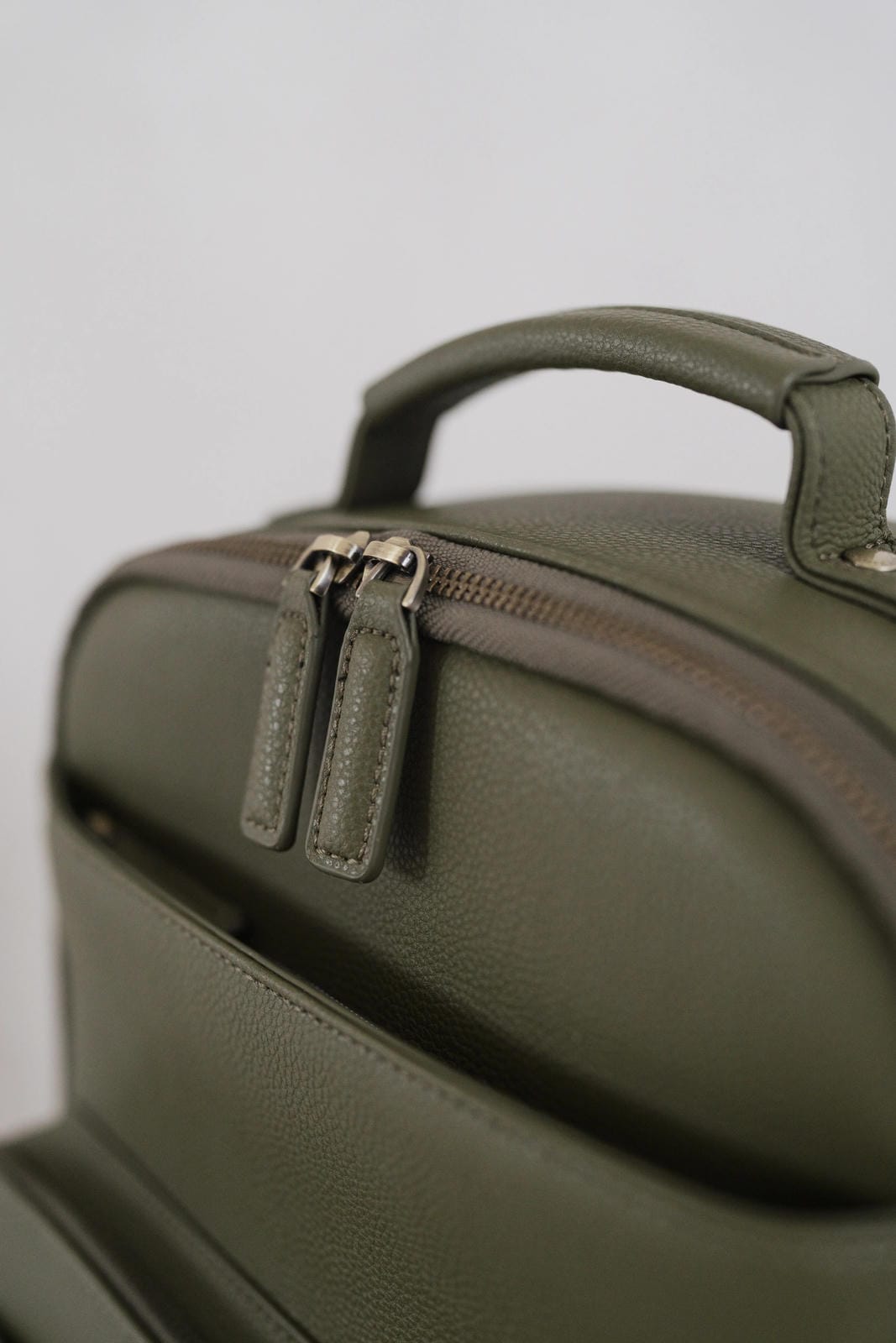 Green leather bag with a zipper on a light gray background