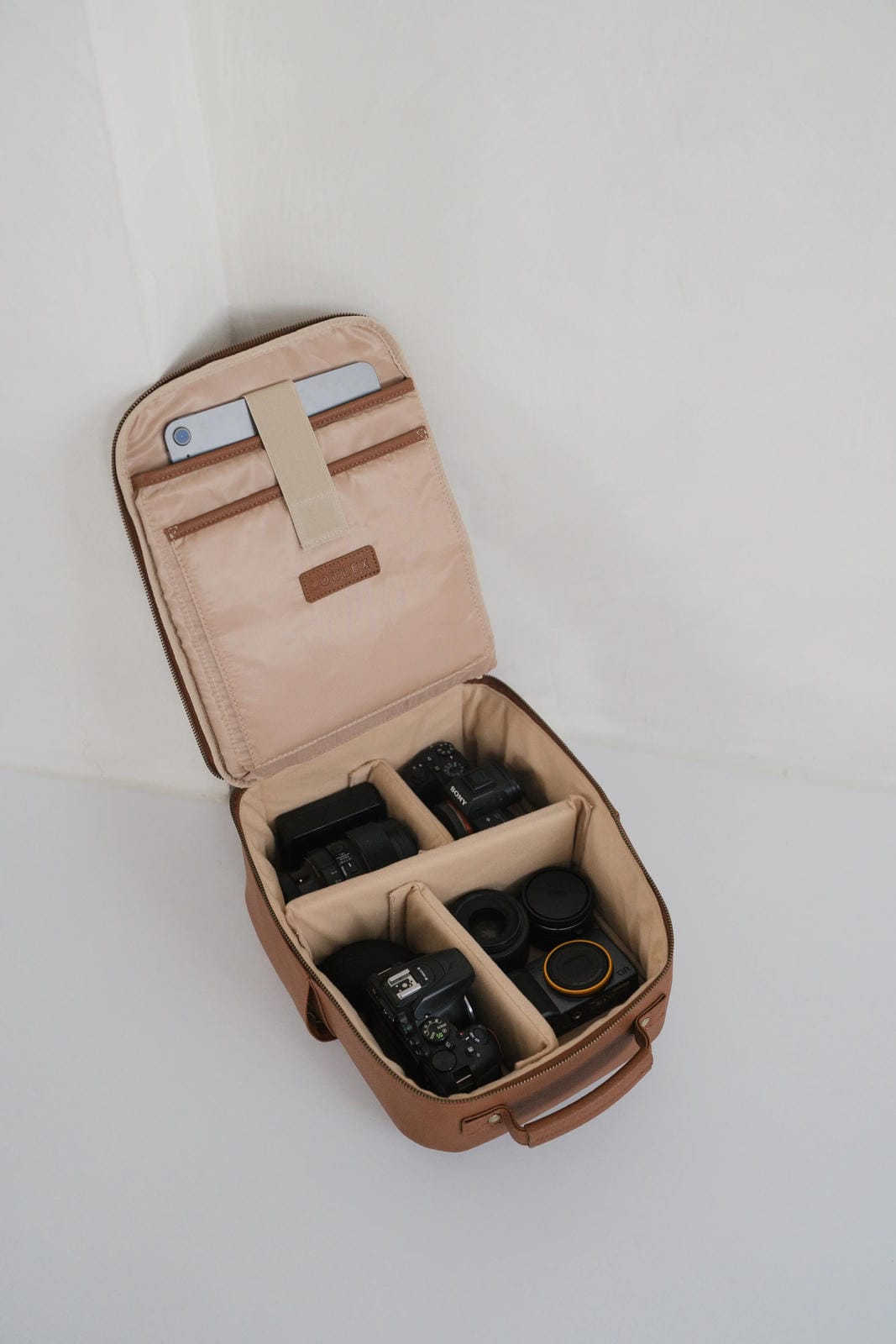 Open beige travel case with compartments for electronic devices on a white background