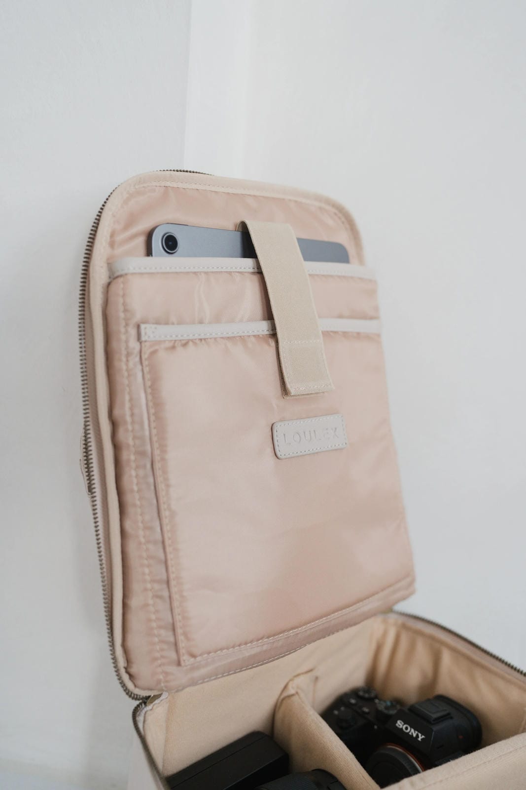 Beige travel wallet with a phone and camera inside on a white background