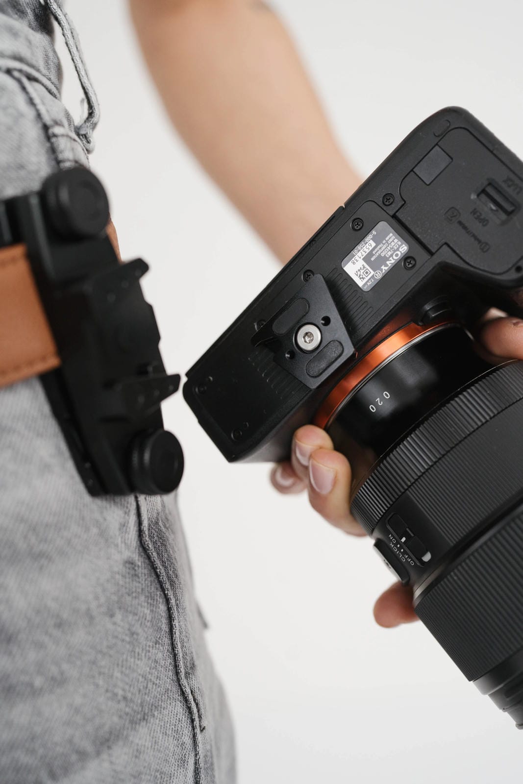 Person holding a camera with a lens attached on a plain background