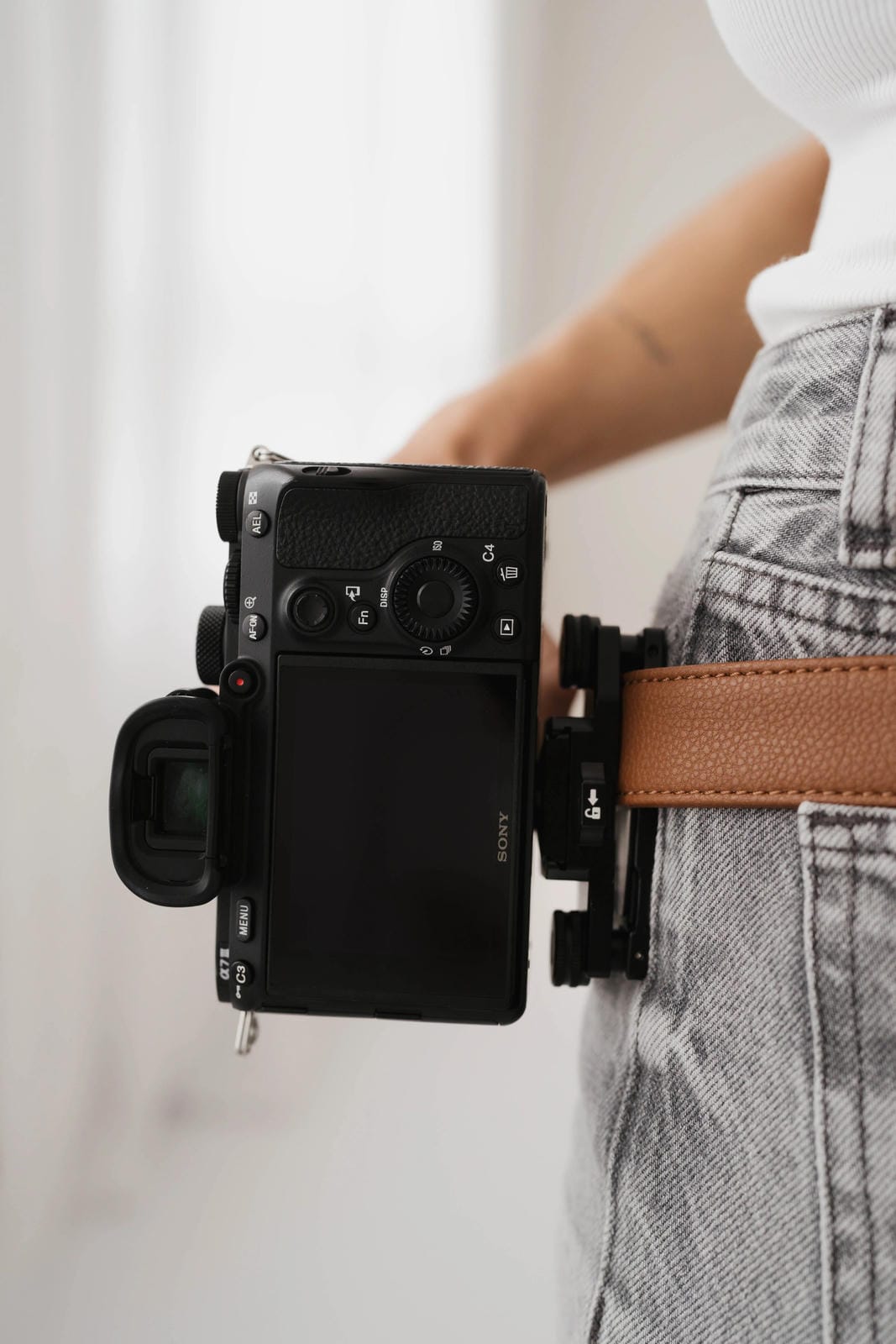 Black camera attached to a person's waist with a neutral background