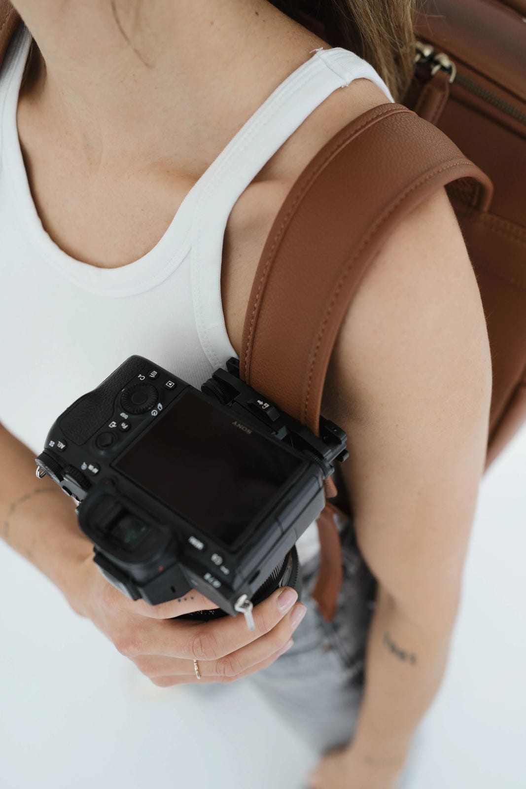 Person holding a camera with a strap over shoulder